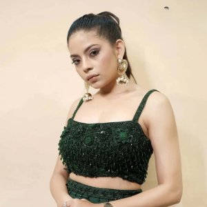 A girl elegantly poses in an emerald green saree adorned with intricate crystal work.
