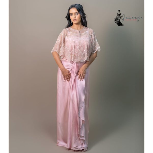 Model wearing a pastel pink draped gown with an embellished sheer cape designed by Juweriya Fashion.